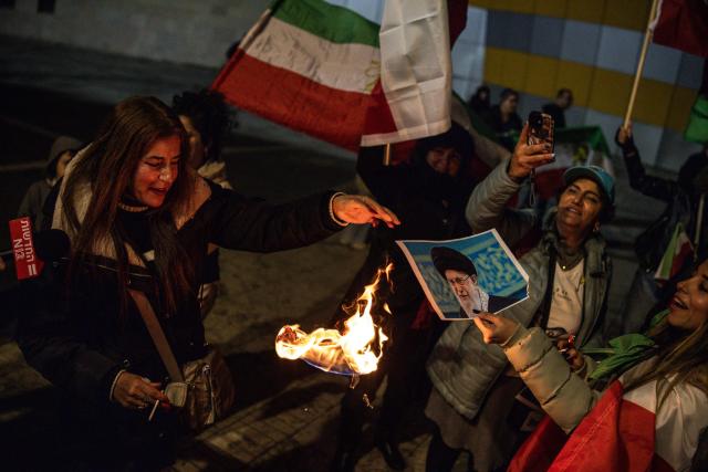People burn a portrait of Iran's Supreme Leader, Ayatollah Ali Khamenei during a demonstration in solidarity with Iranian protestors, in Israel's central city of Holon on January 14, 2026. Iran's long-time foe Israel has openly backed the protesters and expressed optimism about possible regime change, without suggesting it would intervene. (Photo by JOHN WESSELS / AFP)
