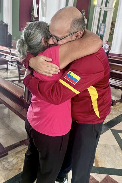 Venezuelan journalist Carlos Julio Rojas (R) is greeted by a relative in a church after being released from prison in Caracas on January 14, 2026. At least nine journalists have been released from prison in Venezuela since Nicolas Maduro's ouster, as the new leadership slowly releases political prisoners, a journalists' union and NGOs reported Wednesday. (Photo by AFP)