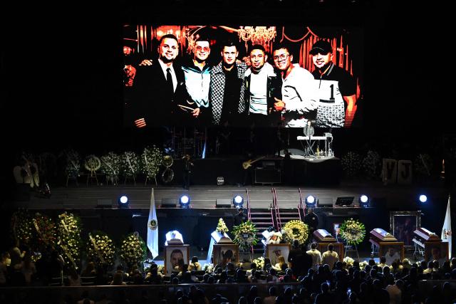 This view shows a photograph (from L) of pilot Fernando Torres, Colombian singer Yeison Jimenez, manager Jefferson Osorio, personal assistant Oscar Marin, photographer Waisman Mora, and visual producer Juan Manuel Rodriguez on a big screen during their funeral honors in Bogota on January 14, 2026. Six people died on january 10, including popular singer Yeison Jimenez, when the small plane they were traveling in crashed shortly after takeoff in central Colombia, authorities said. (Photo by Raul ARBOLEDA / AFP)