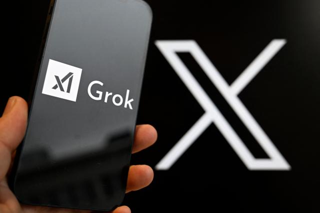 (FILES) This photograph shows a smartphone bearing the logo of Grok, a generative artificial intelligence chatbot developed by US artificial intelligence company xAI in front of the X (formerly Twitter) logo in Brussels on January 12, 2026. Elon Musk's platform X on January 14, 2026 announced measures to prevent its AI chatbot Grok from undressing images of real people, following global backlash over its generation of sexualized images of women and children. (Photo by Nicolas TUCAT / AFP)