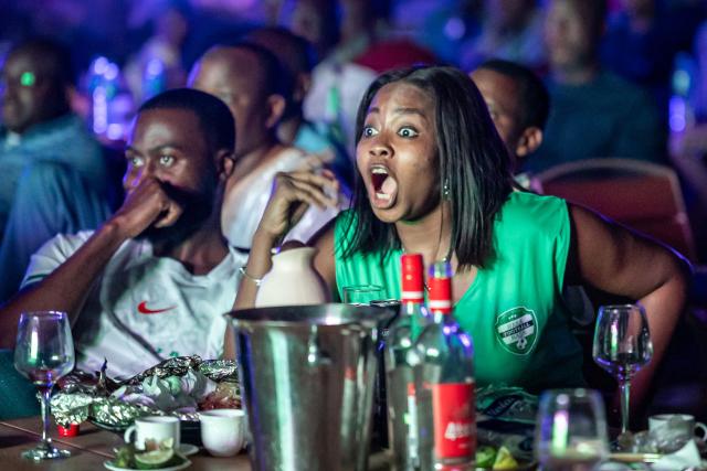 Nigeria football fans react as they watch the Africa Cup of Nations (CAN) semi-final football match between Nigeria and Morocco on a large screen at an outdoor bar in Abuja on January 14, 2026. (Photo by Light Oriye / AFP)