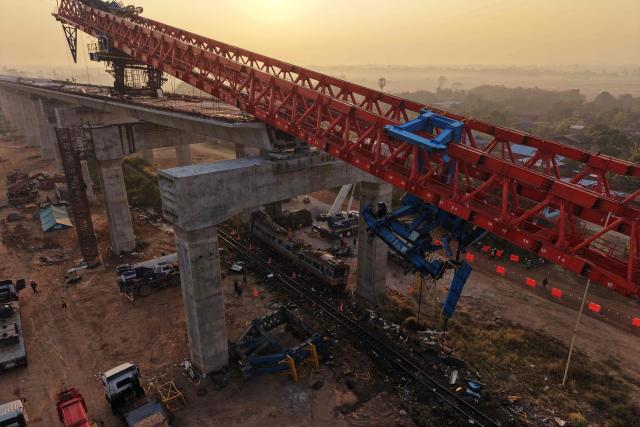 An aerial view shows the wreckage of a train that crashed when a construction crane collapsed the day before, in Thailand's Nakhon Ratchasima province on January 15, 2026. (Photo by Lillian SUWANRUMPHA / AFP)