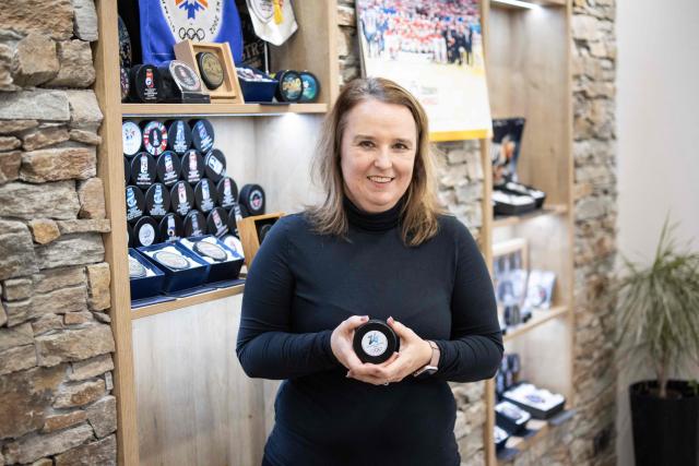 Katerina Zubickova, co-owner of the Czech company Gufex producing ice hockey pucks for the 2026 Olympic Games, poses with a Milan-Cortina puck at the company headquarters in Katerinice village in eastern Czech Republic on December 10, 2025. The Gufex family company produces the black rubber discs for the Milan-Cortina Olympic Winter Games. Milan-Cortina is getting 10,000 pucks for the men's, women's and Paralympic tournaments and another 10,000 souvenir pucks. (Photo by Michal Cizek / AFP)
