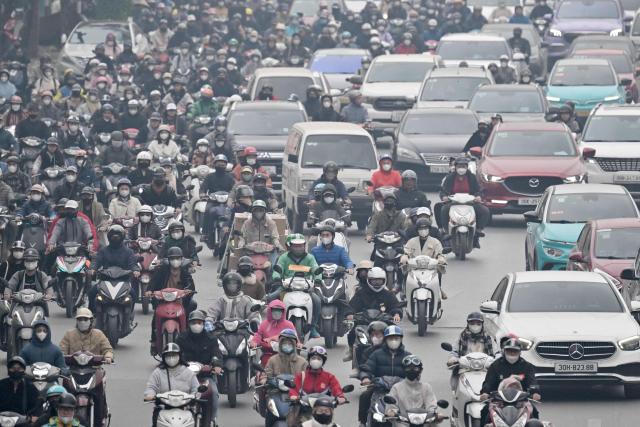 Motorists make their way on a street amid heavy air pollution conditions in Hanoi on January 15, 2026. (Photo by Nhac NGUYEN / AFP)