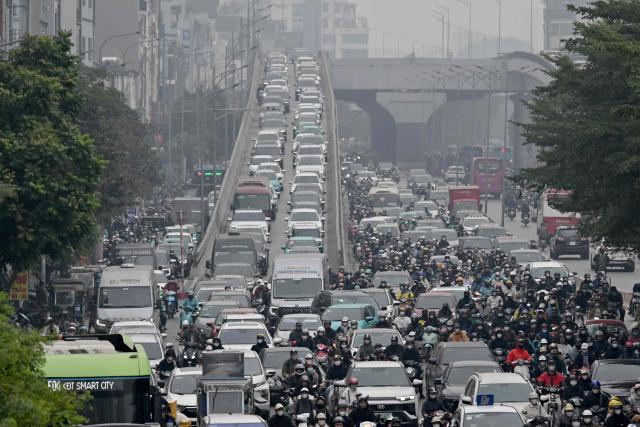 Motorists make their way on a street amid heavy air pollution conditions in Hanoi on January 15, 2026. (Photo by Nhac NGUYEN / AFP)