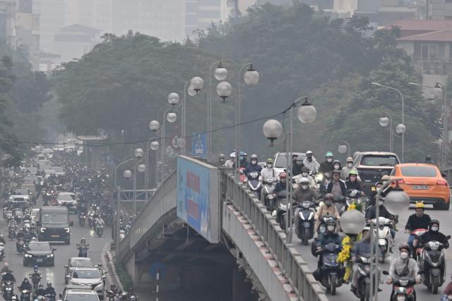 Motorists make their way on a street amid heavy air pollution conditions in Hanoi on January 15, 2026. (Photo by Nhac NGUYEN / AFP)