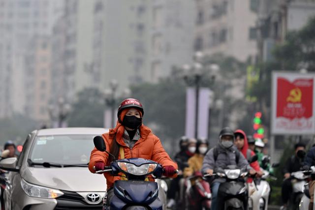 Motorists make their way on a street amid heavy air pollution conditions in Hanoi on January 15, 2026. (Photo by Nhac NGUYEN / AFP)