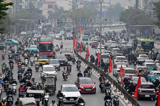 Motorists make their way on a street amid heavy air pollution conditions in Hanoi on January 15, 2026. (Photo by Nhac NGUYEN / AFP)