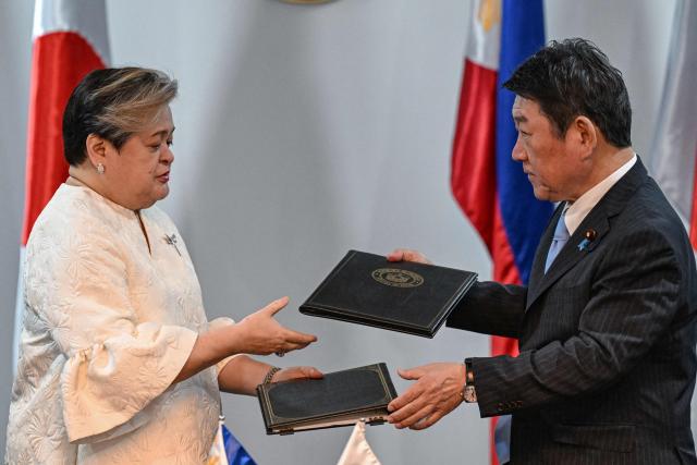 Philippines' Foreign Minister Theresa Lazaro (L) and Japan's Foreign Minister Toshimitsu Motegi exchange documents after signing agreements during a press conference in Pasay, Metro Manila on January 15, 2026. (Photo by Jam STA ROSA / AFP)