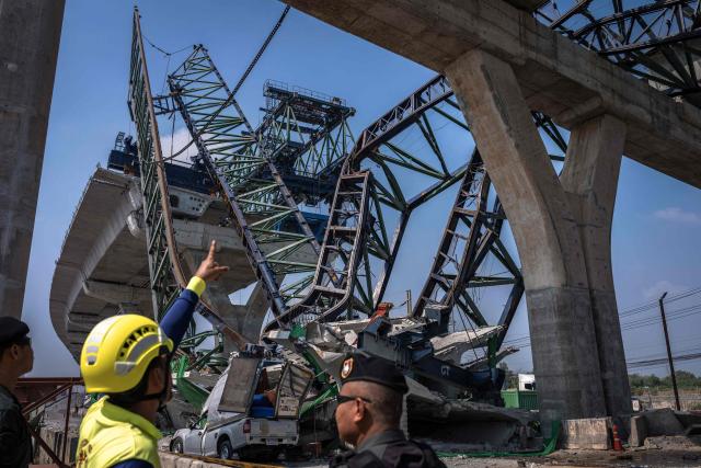 Recovery workers gather at the site of a construction crane collapse onto a highway in Samut Sakhon on the outskirts of Bangkok on January 15, 2026. A crane at a highway construction site in the Bangkok suburbs collapsed on January 15, killing two people, a local police chief told AFP, one day after a crane fell on a train in Thailand, killing 32. (Photo by Chanakarn Laosarakham / AFP)