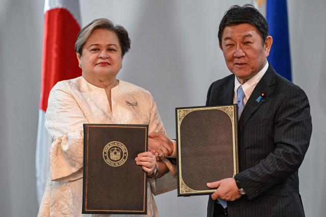Philippines' Foreign Minister Theresa Lazaro (L) and Japan's Foreign Minister Toshimitsu Motegi exchange documents after signing agreements during a press conference in Pasay, Metro Manila on January 15, 2026. (Photo by Jam STA ROSA / AFP)