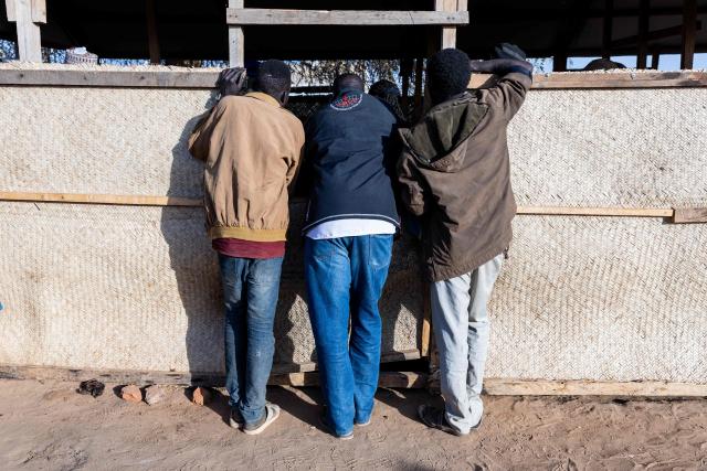 Three Sudanese refugees look inside a shelter at a transit camp in Adre, Ouaddai, on January 14, 2026. (Photo by Joris Bolomey / AFP)