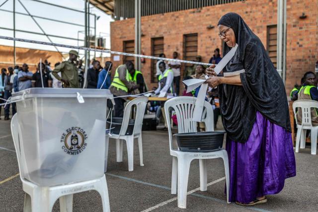 A voter struggles to organise her ballots before marking them on a plastic basin at a school used as a polling station in Kampala on January 15, 2026, during Uganda’s 2026 general elections. (Photo by Luis TATO / AFP)