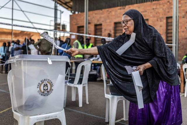 A voter struggles to organise her ballots before casting them into a ballot box at a school used as a polling station in Kampala on January 15, 2026, during Uganda’s 2026 general elections. (Photo by Luis TATO / AFP)