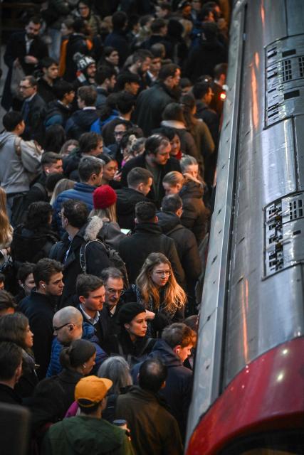 Commuters exit and board a train on the platform at Earls Court Tube station in London on January 15, 2026. Britain's economy grew more than expected in November, official data showed on January 15, handing a boost to the Labour government after recent weak figures. (Photo by JUSTIN TALLIS / AFP)