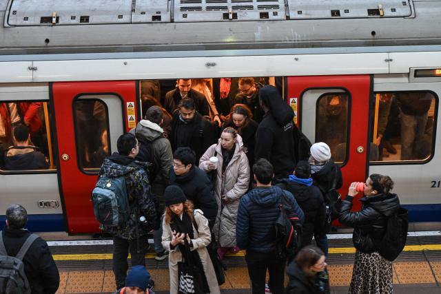 Commuters exit and board a train on the platform at Earls Court Tube station in London on January 15, 2026. Britain's economy grew more than expected in November, official data showed on January 15, handing a boost to the Labour government after recent weak figures. (Photo by JUSTIN TALLIS / AFP)