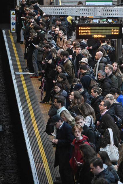 Commuters wait to board a train at Earls Court Tube station in London on January 15, 2026. Britain's economy grew more than expected in November, official data showed on January 15, handing a boost to the Labour government after recent weak figures. (Photo by JUSTIN TALLIS / AFP)
