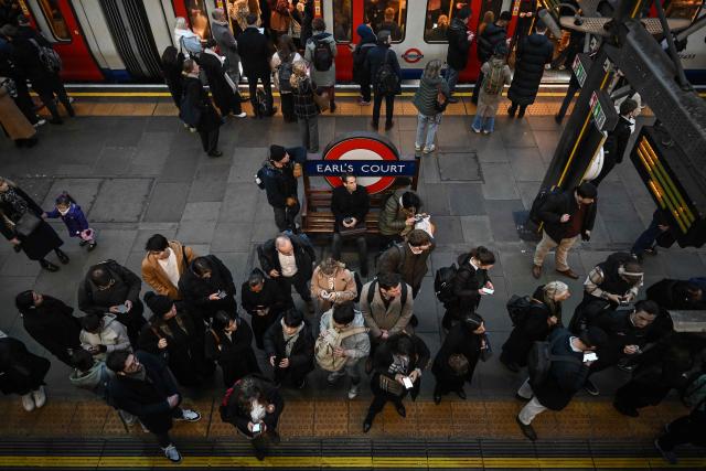 Commuters exit and board a train on the platform at Earls Court Tube station in London on January 15, 2026. Britain's economy grew more than expected in November, official data showed on January 15, handing a boost to the Labour government after recent weak figures. (Photo by JUSTIN TALLIS / AFP)
