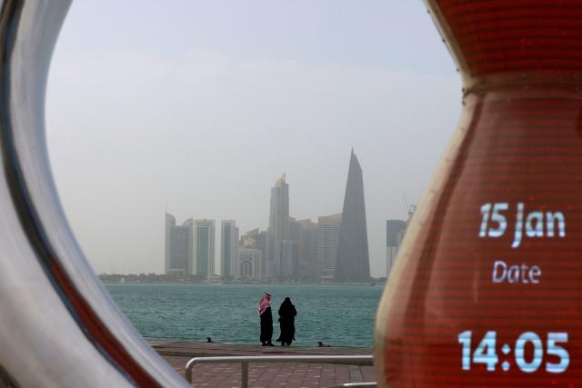 Visitors walk along the waterfront on a foggy day at the Corniche area facing the high-rise buildings in the West Bay district, in Doha on January 15, 2026. (Photo by Karim JAAFAR / AFP)