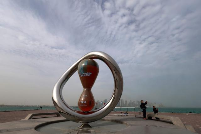 Visitors take pictures next to the 2022 FIFA World Cup countdown clock installed along the waterfront on a foggy day at the Corniche area facing the high-rise buildings in the West Bay district, in Doha on January 15, 2026. (Photo by Karim JAAFAR / AFP)
