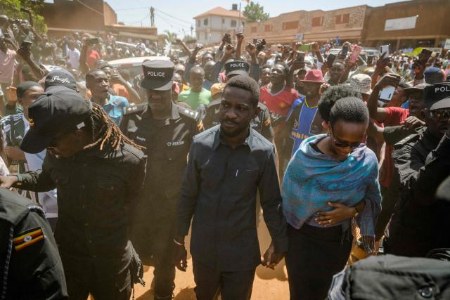 TOPSHOT - Uganda opposition leader and National Unity Platform (NUP) presidential candidate Robert Kyagulanyi Ssentamu, popularly known as Bobi Wine (C), and his wife Barbara Kyagulanyi (CR) arrive to casts their ballots in Kampala on January 15, 2026, during Uganda’s 2026 general elections. (Photo by Rian COPE / AFP)