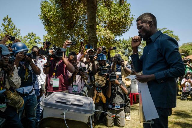 Uganda opposition leader and National Unity Platform (NUP) presidential candidate Robert Kyagulanyi Ssentamu, popularly known as Bobi Wine (R), gestures before casting his ballot in Kampala on January 15, 2026, during Uganda’s 2026 general elections. (Photo by Rian COPE / AFP)