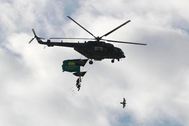 Iraqi army soldiers with flags fly past in a Mi-8 military transport helicopter near the shrine of the 8th-century Imam Musa al-Kadhim, during the annual commemoration of his death on 25 Rajab according to the Muslim Hijri calendar, in the Kadhimiya district of northern Baghdad on January 15, 2026. Pilgrims from various Iraqi provinces annually undertake a march on foot to reach the shrine to commemorate the death of Imam Kadhim, who is believed to have been poisoned by agents of the ruling Abbasid caliph Harun al-Rashid. (Photo by AHMAD AL-RUBAYE / AFP)