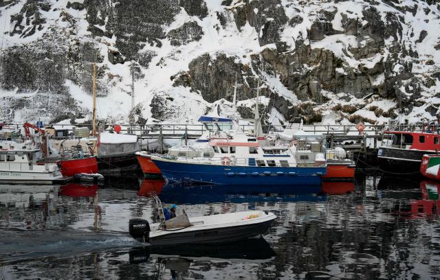 A fisherman steers his boat past moored fishing vessels in the harbour in Nuuk, Greenland, on January 15, 2026. Denmark's prime minister said on January 15, 2026 that the US ambition to take control of Greenland remained "intact" and that there were still a "fundamental disagreement" between the countries, despite high-stakes White House talks. (Photo by Alessandro Rampazzo / AFP)