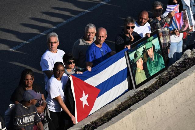 Cubans bid farewell to the funeral procession carrying the remains of the 32 Cuban soldiers who died during the US incursion to capture Venezuelan leader Nicolas Maduro, at the Boyeros Avenue in Havana on January 15, 2026. The capture by US forces of Venezuelan leader Nicolas Maduro on January 3, 2026, and the killing in the operation of 32 Cubans assigned to protect him represent a major blow for the island's revered intelligence services, experts say. (Photo by Yamil LAGE / AFP)