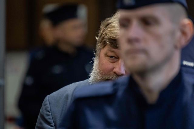 Russian defendant Alexandre Boutiaguine (Alexander Butiagin) (C) is escorted by Polish police officers to the courtroom of Warsaw's Regional Court in Warsaw, Poland on January 15, 2026for extradition procedure to Ukraine, where he is to be put on trial for conducting excavations in the occupied territory of the Crimean peninsula. The case was postponed without setting a date as a result of the defense's motion to change the presiding judge. (Photo by Wojtek RADWANSKI / AFP)