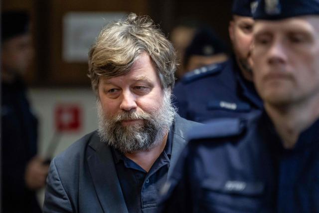 Russian defendant Alexandre Boutiaguine (Alexander Butiagin) (C) is escorted by Polish police officers to the courtroom of Warsaw's Regional Court in Warsaw, Poland on January 15, 2026for extradition procedure to Ukraine, where he is to be put on trial for conducting excavations in the occupied territory of the Crimean peninsula. The case was postponed without setting a date as a result of the defense's motion to change the presiding judge. (Photo by Wojtek RADWANSKI / AFP)