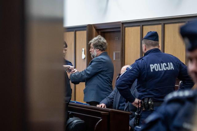 Polish police officers put handcuffs on Russian defendant Alexandre Boutiaguine (Alexander Butiagin) (L) before leading him out of the courtroom of Warsaw's Regional Court in Warsaw, Poland on January 15, 2026, after extradition procedure to Ukraine, where he is to be put on trial for conducting excavations in the occupied territory of the Crimean peninsula. The case was postponed without setting a date as a result of the defense's motion to change the presiding judge. (Photo by Wojtek RADWANSKI / AFP)