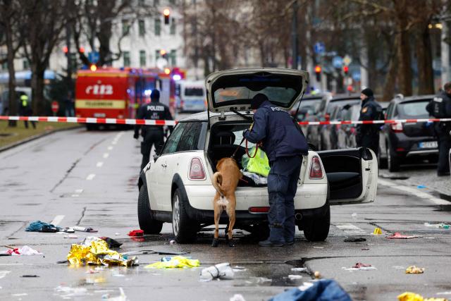 (FILES) A police officer uses a dog to search the car at the scene where a man drove into a crowd in the southern German city of Munich on February 13, 2025 leaving several people injured, police said. An Afghan man, partially identified as Farhad N., goes on trial in Germany on January 16, 2026 accused of ramming a car into a crowd in Munich last year, killing a two-year-old girl and her mother and injuring dozens. The suspect faces two charges of murder and 44 of attempted murder, with prosecutors saying he acted out of a "religious motivation" and expected to die in the attack. Farhad N., who was 24 at the time of the attack, is accused of deliberately driving his car, a BMW Mini, into a 1,400-strong trade union street rally in Munich on February 13. (Photo by Michaela STACHE / AFP)