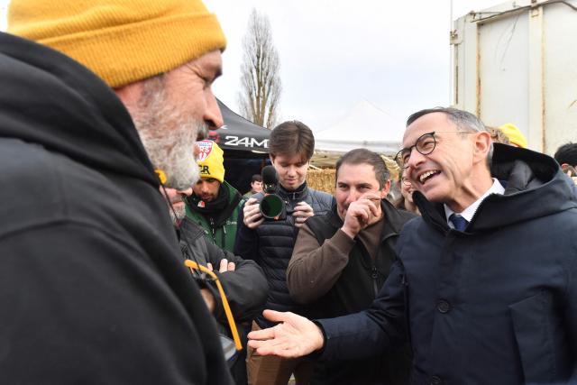 President of Les Republicains (LR) right wing party Bruno Retailleau (R) talks with farmers of the French farmer union Coordination Rurale blocking an oil depot during a protest against the EU-Mercosur trade deal in Saint-Pierre-des-Corps, central France, on January 15, 2026. (Photo by JEAN-FRANCOIS MONIER / AFP)