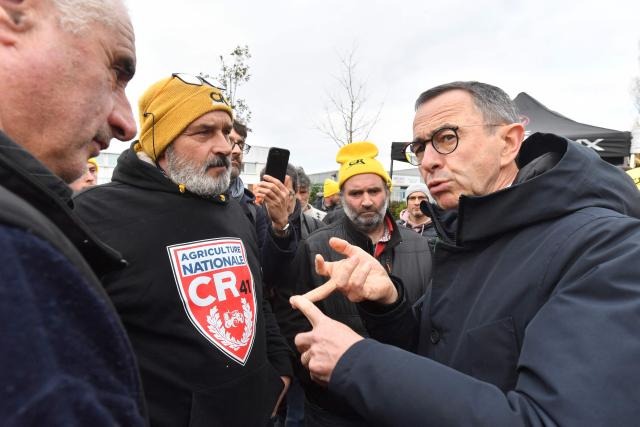 President of Les Republicains (LR) right wing party Bruno Retailleau (R) talks with farmers of the French farmer union Coordination Rurale blocking an oil depot during a protest against the EU-Mercosur trade deal in Saint-Pierre-des-Corps, central France, on January 15, 2026. (Photo by JEAN-FRANCOIS MONIER / AFP)