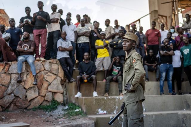A Ugandan police officer monitors the areas as a crowd of residents follows the vote-counting process at a public ground used as a polling station in Kampala on January 15, 2026, during Uganda’s 2026 general elections. (Photo by Luis TATO / AFP)