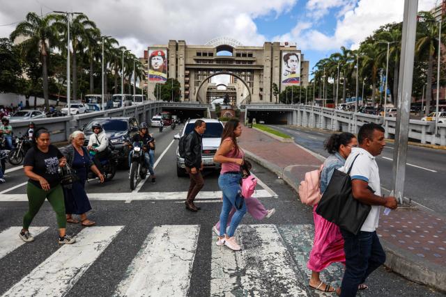 People cross Bolivar Avenue in Caracas on January 15, 2026. Venezuelan opposition leader Maria Corina Machado arrived at the White House on January 15 for talks with US President Donald Trump, who has sidelined her since toppling Nicolas Maduro -- and who openly covets her Nobel Peace Prize. (Photo by Pedro MATTEY / AFP)