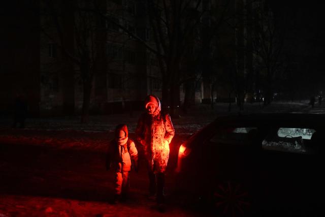 Pedestrians walk along a street during a power outage in Kyiv on January 15, 2026, amid the Russian invasion of Ukraine. (Photo by Sergei GAPON / AFP)