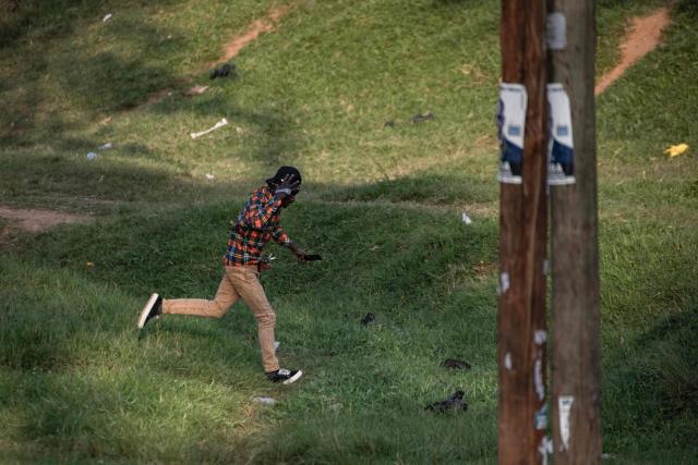 A pedestrian flees as military police intervene, on the sidelines of votes being counted at a polling station in Kampala on January 15, 2026, during Uganda's 2026 general elections. Polls closed in Uganda on January 15, 2026 after a chaotic day of voting that took place under an internet blackout and with long delays caused by technical breakdowns as President Yoweri Museveni seeks to extend his 40 years in power. Museveni, an 81-year-old who came to power at the head of a rebel army in 1986, is widely expected to win a seventh term in office thanks to his total control of the state and security apparatus. (Photo by BADRU KATUMBA / AFP)