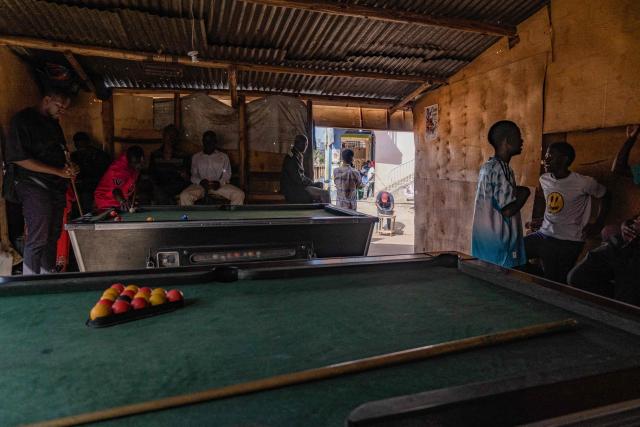 Men play pool at a kiosk next to a polling station in Kampala on January 15, 2026, during Uganda's 2026 general elections. Polls closed in Uganda on January 15, 2026 after a chaotic day of voting that took place under an internet blackout and with long delays caused by technical breakdowns as President Yoweri Museveni seeks to extend his 40 years in power. Museveni, an 81-year-old who came to power at the head of a rebel army in 1986, is widely expected to win a seventh term in office thanks to his total control of the state and security apparatus. (Photo by Badru Katumba / AFP)