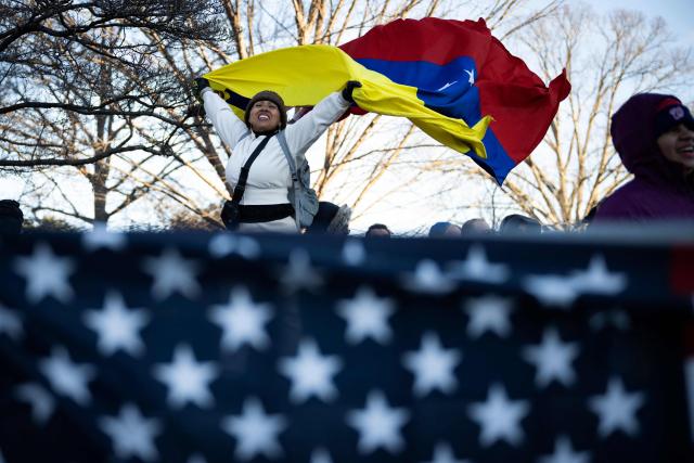 A woman waves a Venezuelan flag as she waits for opposition leader Maria Corina Machado to exit the US Capitol following a meeting with US senators on January 15, 2026 in Washington, DC. US President Donald Trump met earlier Thursday with Venezuelan opposition leader Machado, whose pro-democracy movement he has sidelined since toppling her country's leader, and whose Nobel Peace Prize he openly envies. (Photo by Drew ANGERER / AFP)