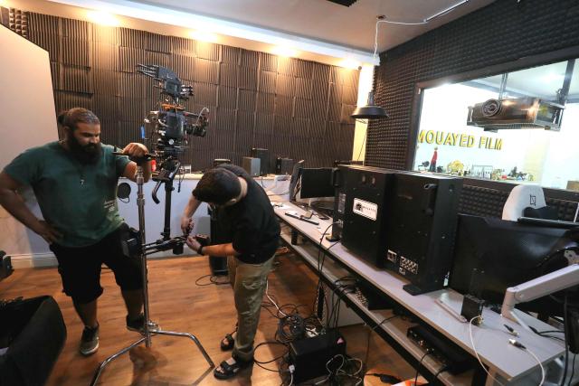 Members of the crew prepare their equipment prior to filming in studios built inside the home of the Libyan filmmaker in Tripoli on October 19, 2025. Mouayed Zabtia, 47, shoots most scenes for his latest movie in a studio he built at his Tripoli home. For the filmmaker, it is one way to overcome the obstacles he faces in a country where cinema once nearly vanished. Before a 1969 coup that brought longtime ruler Moamer Kadhafi to power, Libya's capital Tripoli was home to more than 20 movie theatres. Today, Zabtia said, it is no longer censorship that stifles filmmaking in Libya, but an array of other challenges compounded by a lack of public support. (Photo by Mahmud TURKIA / AFP)