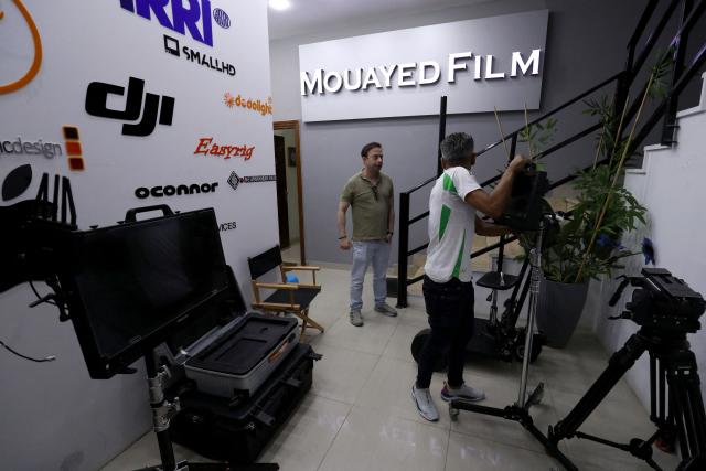 Libyan filmaker Mouayed Zabtia speaks to a member of his crew (R) at his home-come-studio, in Tripoli on October 19, 2025. Mouayed Zabtia, 47, shoots most scenes for his latest movie in a studio he built at his Tripoli home. For the filmmaker, it is one way to overcome the obstacles he faces in a country where cinema once nearly vanished. Before a 1969 coup that brought longtime ruler Moamer Kadhafi to power, Libya's capital Tripoli was home to more than 20 movie theatres. Today, Zabtia said, it is no longer censorship that stifles filmmaking in Libya, but an array of other challenges compounded by a lack of public support. (Photo by Mahmud TURKIA / AFP)