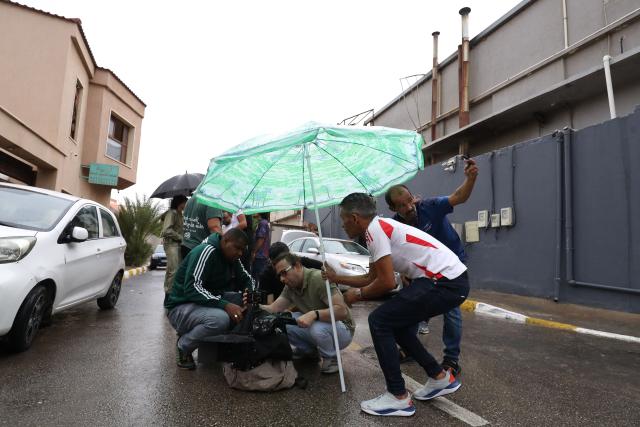 Libyan filmmaker Mouayed Zabtia (C) directs his crew during filming outside his home-come-studio, in Tripoli on October 19, 2025. Mouayed Zabtia, 47, shoots most scenes for his latest movie in a studio he built at his Tripoli home. For the filmmaker, it is one way to overcome the obstacles he faces in a country where cinema once nearly vanished. Before a 1969 coup that brought longtime ruler Moamer Kadhafi to power, Libya's capital Tripoli was home to more than 20 movie theatres. Today, Zabtia said, it is no longer censorship that stifles filmmaking in Libya, but an array of other challenges compounded by a lack of public support. (Photo by Mahmud TURKIA / AFP)