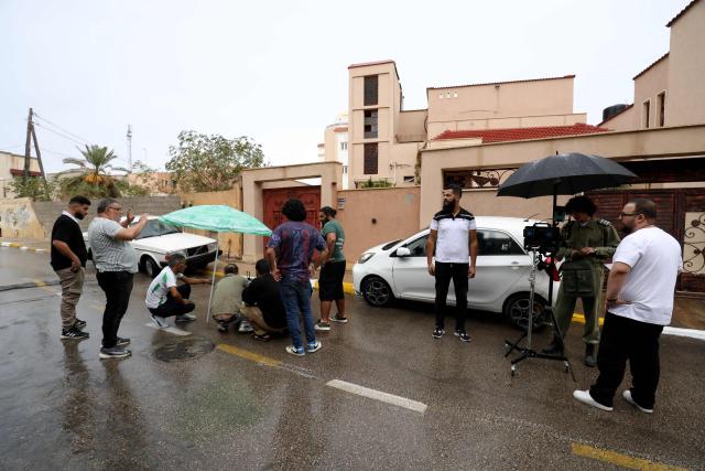 Libyan filmmaker Mouayed Zabtia (C) directs his crew during filming outside his home-come-studio, in Tripoli on October 19, 2025. Mouayed Zabtia, 47, shoots most scenes for his latest movie in a studio he built at his Tripoli home. For the filmmaker, it is one way to overcome the obstacles he faces in a country where cinema once nearly vanished. Before a 1969 coup that brought longtime ruler Moamer Kadhafi to power, Libya's capital Tripoli was home to more than 20 movie theatres. Today, Zabtia said, it is no longer censorship that stifles filmmaking in Libya, but an array of other challenges compounded by a lack of public support. (Photo by Mahmud TURKIA / AFP)