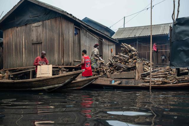 People carry wares from a pirogue in Makoko, a floating slum in Lagos, on January 9, 2026. Authorities have demolished hundreds of wooden shacks in Makoko, Africa’s largest and most iconic floating slum, which is built on stilts above the lagoon in the heart of Lagos. The operation is part of an ongoing campaign to remove what officials describe as illegal structures and reclaim waterfront land for modern real-estate developments. (Photo by TOYIN ADEDOKUN / AFP)