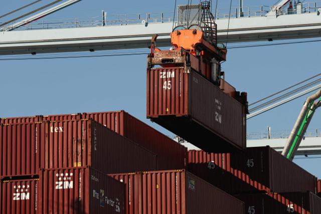 A crane unloads a cargo shipping container from a ship docked at the International Transportation Service (ITS) terminal at the Port of Long Beach in Long Beach, California on January 14, 2026. (Photo by Patrick T. Fallon / AFP)