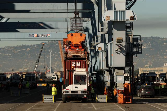 A crane loads a truck with a cargo shipping container from a ship docked at the International Transportation Service (ITS) terminal at the Port of Long Beach in Long Beach, California on January 14, 2026. (Photo by Patrick T. Fallon / AFP)