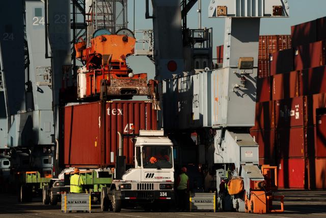 A crane loads a truck with a cargo shipping container from a ship docked at the International Transportation Service (ITS) terminal at the Port of Long Beach in Long Beach, California on January 14, 2026. (Photo by Patrick T. Fallon / AFP)