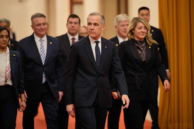 Canada's Prime Minister Mark Carney (C) arrives for meeting with Chinese President Xi Jinping at the Great Hall of the People in Beijing on January 16, 2026. (Photo by Vincent Thian / POOL / AFP)